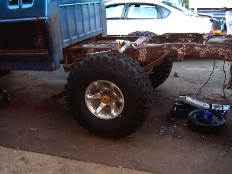 1988 Ford F-250 - A blue truck cab sits on a rusty chassis with large tires, undergoing repairs.