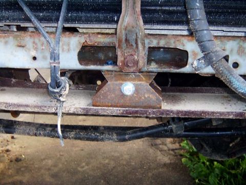 1988 Ford F-250 - The front end of a vehicle shows significant rust and wear on its structural components and hoses.