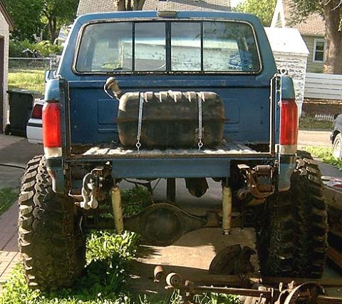 1988 Ford F-250 - This blue pickup truck features oversized tires and an auxiliary fuel tank, suggesting modifications for off-road use or extended range.