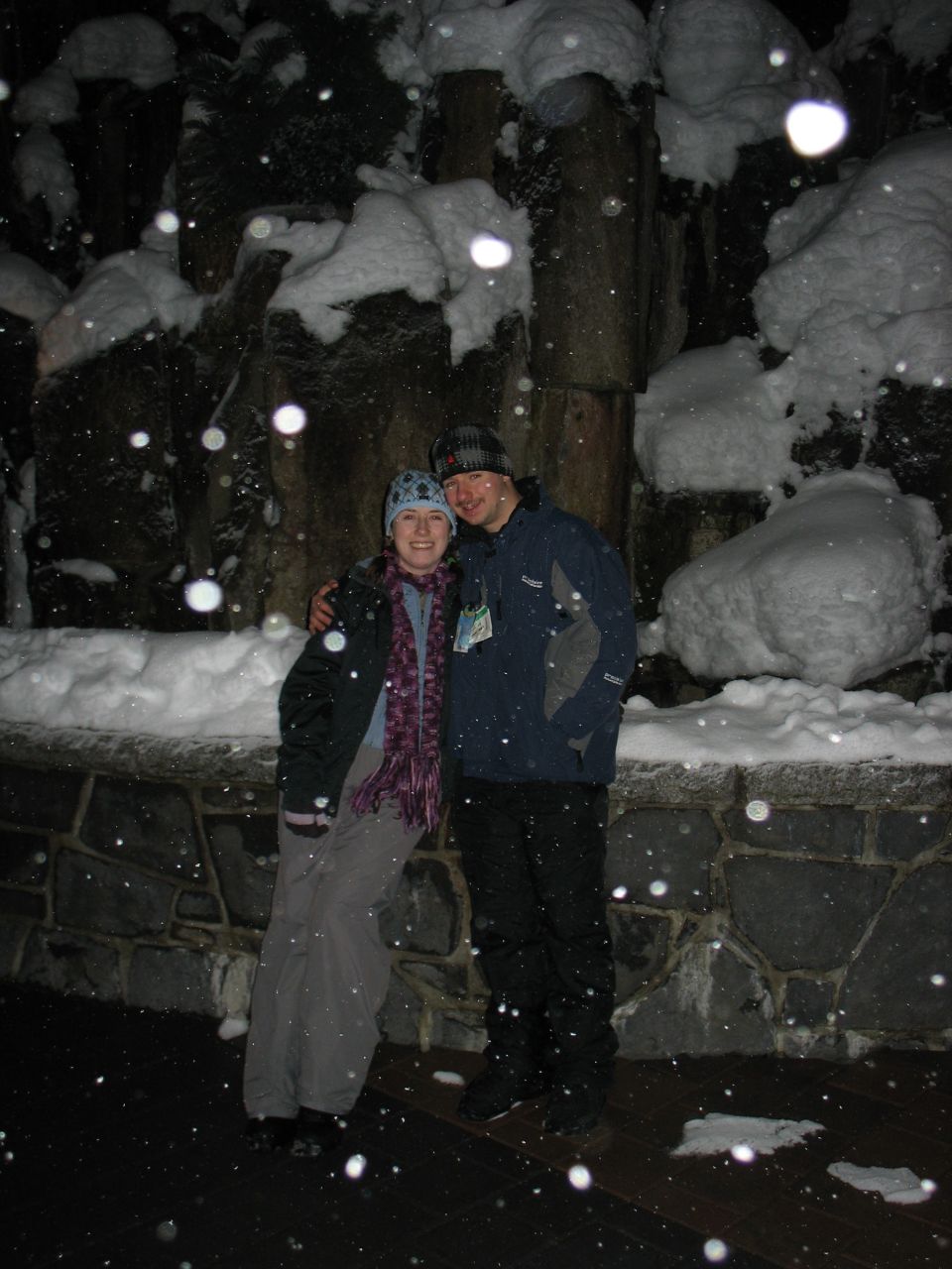 Couple posing in a snowy environment with snow falling