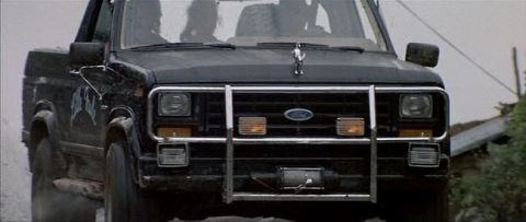 1991 Ford Bronco - Front view of a black Ford Bronco with a bull bar and winch, showing its distinctive grille and hood ornament.