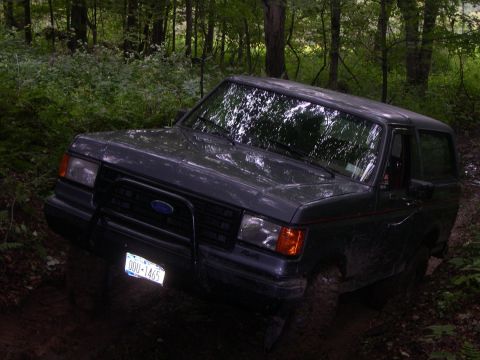 1989 Ford Bronco - A 1989 Ford Bronco navigates a wooded, off-road trail.