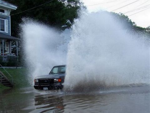1989 Ford Bronco - A truck drives through a flooded area, sending water high into the air on both sides.