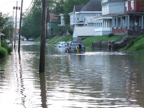 1989 Ford Bronco - A street is flooded, with a van and another car partially submerged in the water.