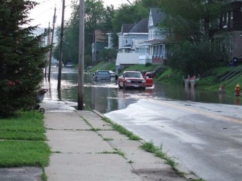 1989 Ford Bronco - A red pickup truck navigates flooded streets, with other vehicles visible in the background.