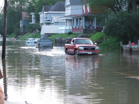 1989 Ford Bronco - Floodwaters inundate a residential street, with a GMC pickup navigating the high water.