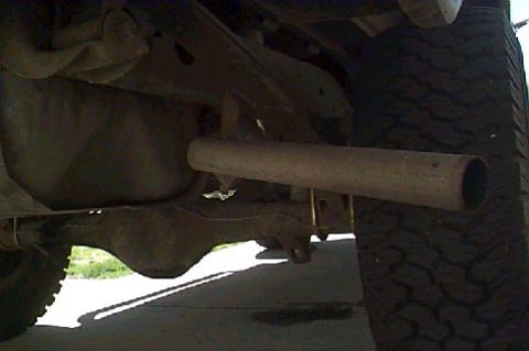 1980 Ford Bronco - Close-up of the rear axle and exhaust system of a vehicle, with a tire in the background.