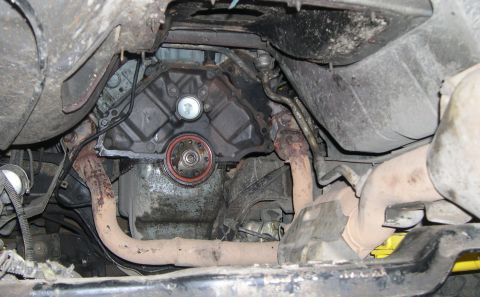 1989 Ford Bronco - Underside view of a vehicle's engine and exhaust system, with a focus on the transmission seal and rusty exhaust pipes.