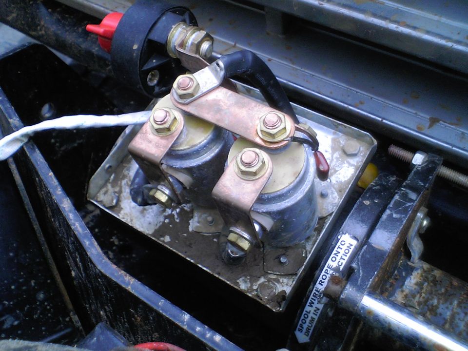 Dual starter solenoids mounted on a metal plate in an engine bay