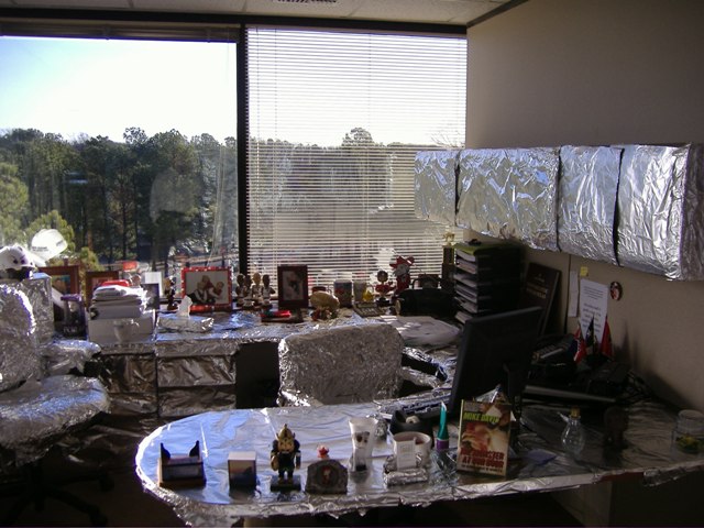 Office cubicle desks and shelves completely wrapped in aluminum foil as a prank