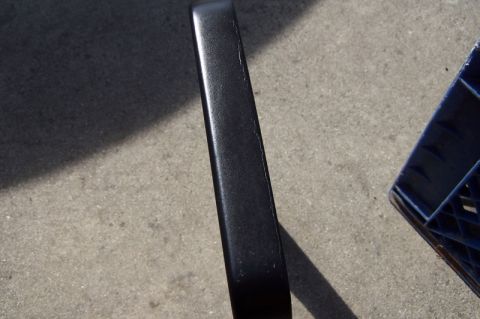 1990 Ford Bronco - A black trim piece is shown on a concrete surface, with a blue plastic crate visible to the right.