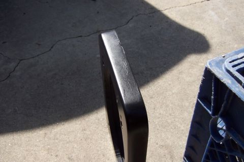 1990 Ford Bronco - Close-up of a black plastic trim piece, possibly automotive, resting on concrete.