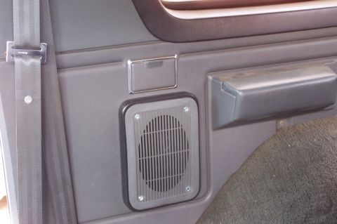 1990 Ford Bronco - Close-up of a vehicle's interior door panel, highlighting the speaker and seatbelt assembly.