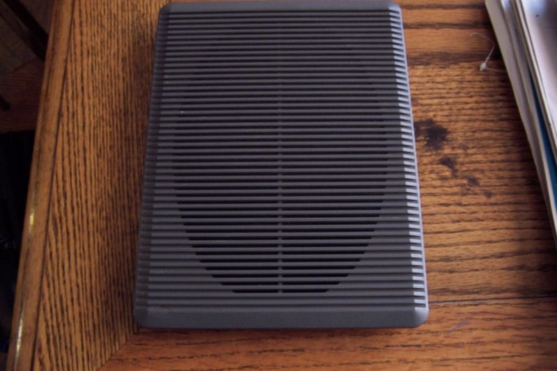 Gray speaker adapter with horizontal grille on wooden surface