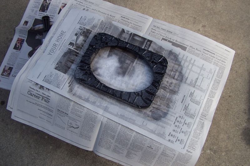 Black speaker adapter with textured surface, resting on newspapers