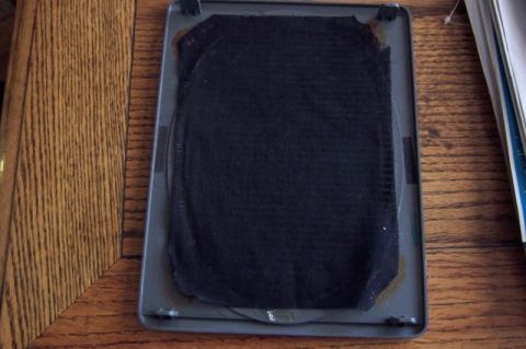 1990 Ford Bronco - A speaker adapter part is shown on a wooden surface. The part has a black fabric covering.
