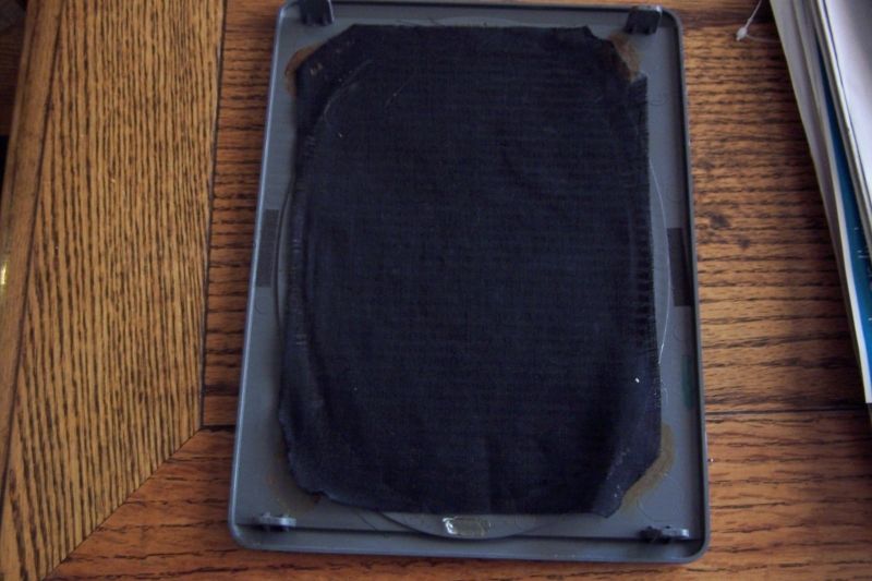 Speaker adapter part with black fabric covering a gray plastic frame