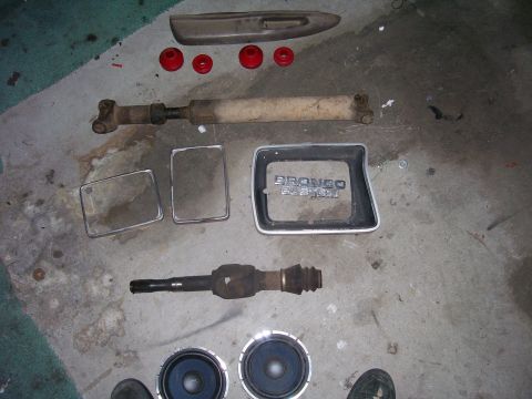 1991 Ford Bronco - Collection of parts for a 1991 Ford Bronco, including the emblem, driveshaft, and speakers.