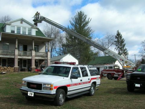 1989 Ford Bronco - Emergency vehicles including a ladder truck and GMC SUV are on scene near a house.