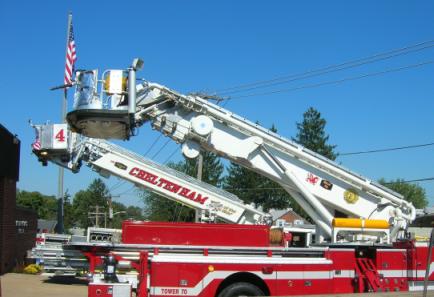 1989 Ford Bronco - A fire truck with an extended ladder is parked outdoors under a clear blue sky.