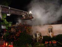 1989 Ford Bronco - Firefighters battle a house fire at night, with smoke billowing from the roof.