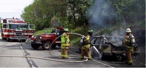 1989 Ford Bronco - Firefighters battle a car fire on the roadside, with a fire engine and a Jeep nearby.
