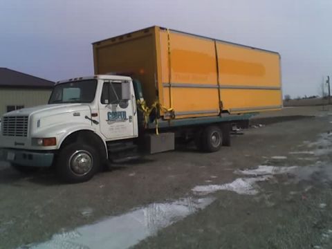 1992 Ford Bronco - A white International box truck with a large yellow cargo container is parked on a gravel lot.