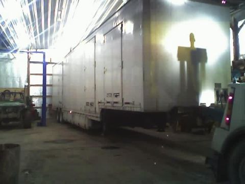 1992 Ford Bronco - Workshop scene with a large trailer and a truck, no 1992 Ford Bronco visible.