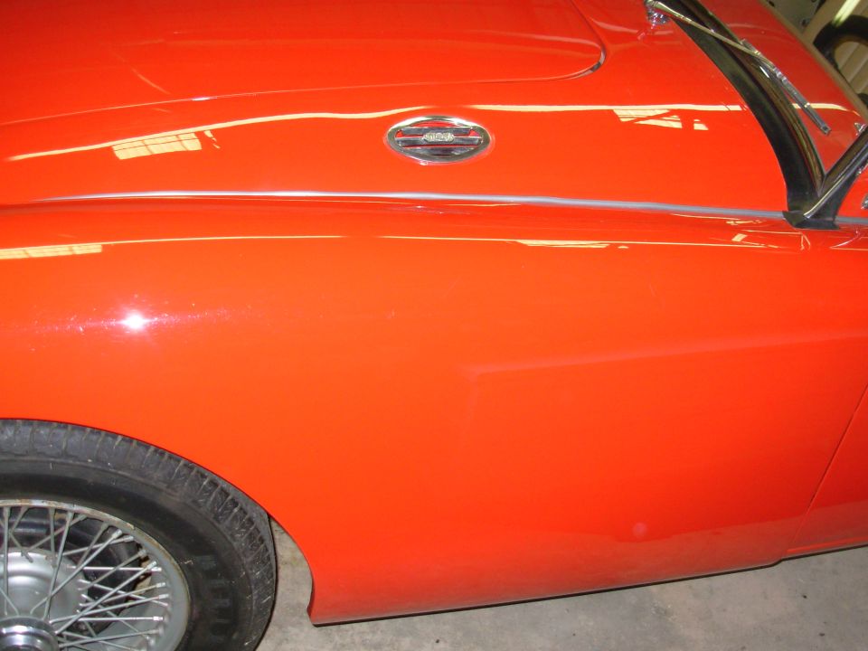 Red MG A front fender with MG badge, chrome trim, and wire-spoke wheel