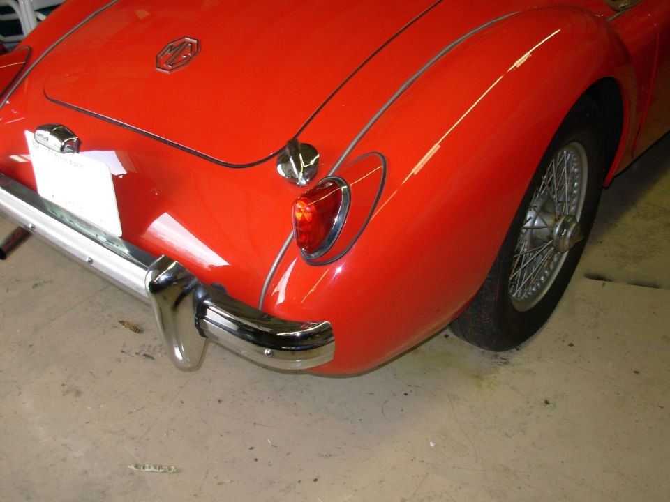 Red 1959 MG A rear quarter panel with chrome bumper and wire wheel