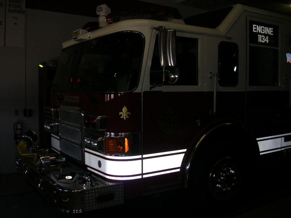 Red and white fire engine parked in a station at night