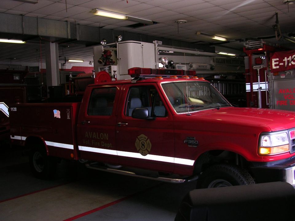 Red Ford F-350 crew cab fire department pickup parked in a fire station bay