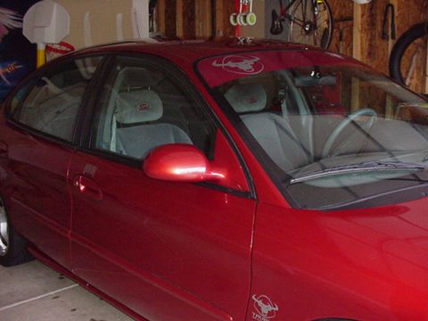1998 Ford Taurus - The side profile of a red sedan is visible, parked indoors with a glimpse of the interior.