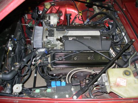 1992 Jaguar XJ-S - The engine bay of a red vehicle, showing a V8 engine with visible Jaguar branding on a component.