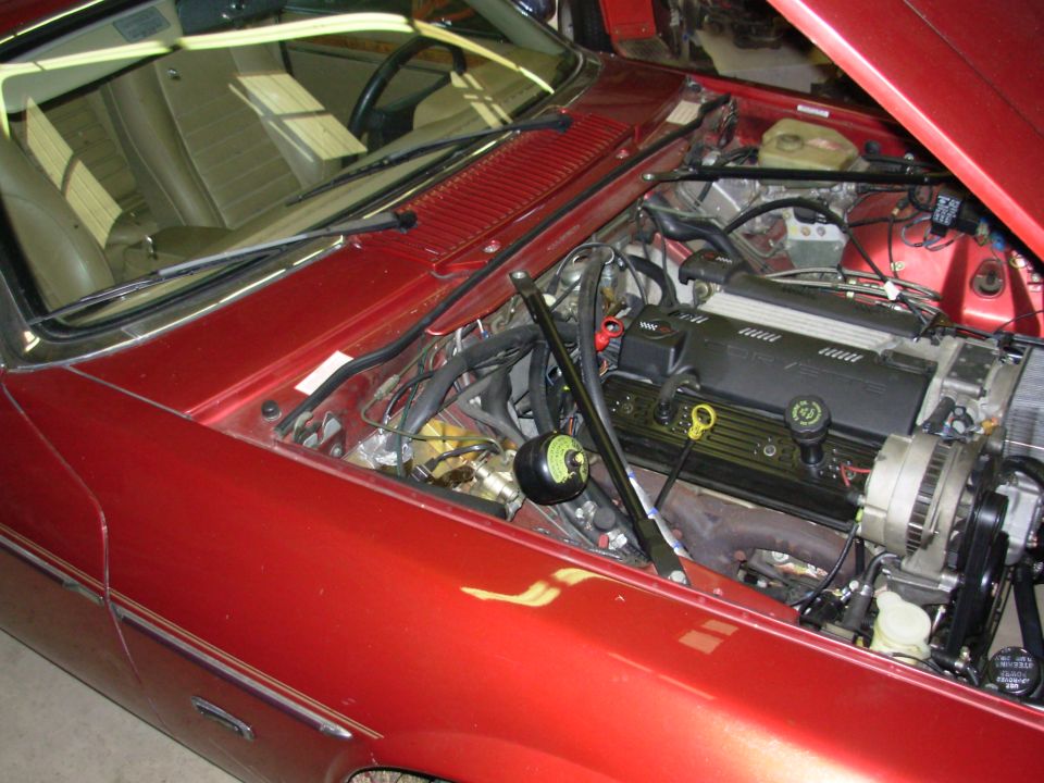 Red car engine bay with V8 engine and visible wiring