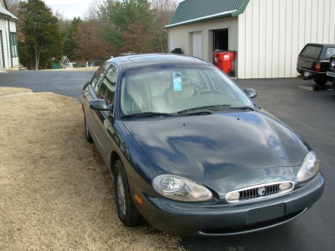 1999 Mercury Sable - A 1999 Mercury Sable sedan is parked on a paved surface next to a grassy area.