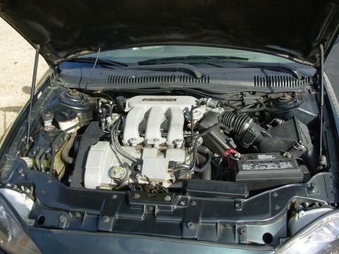 1999 Mercury Sable - The engine compartment of a car is open, showing the V6 engine and its components.