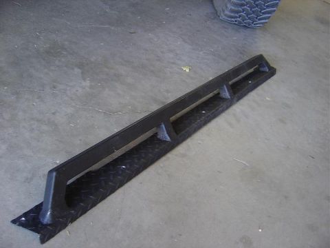 1986 Ford Bronco II - A black diamond plate step with a black metal bar is shown on a concrete floor.