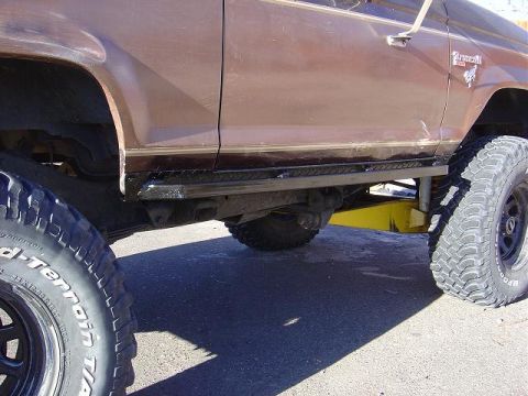 1986 Ford Bronco II - Side view of a 1986 Ford Bronco II, aftermarket diamond plate steps and large off-road tires.