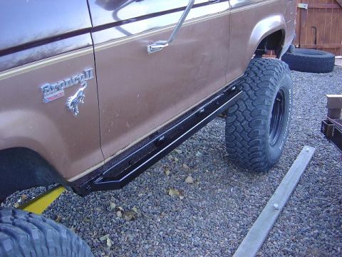 1986 Ford Bronco II - A brown 1986 Ford Bronco II is shown from the side, equipped with aftermarket side steps and off-road tires.