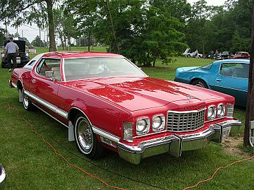1976 Ford Thunderbird - A red 1977 Ford Thunderbird coupe is seen from a three-quarter front angle, parked outdoors with another vehicle in the background.