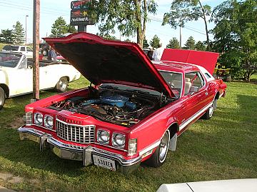1976 Ford Thunderbird - A red 1976 Ford Thunderbird coupe is shown with its hood open, revealing the engine bay.
