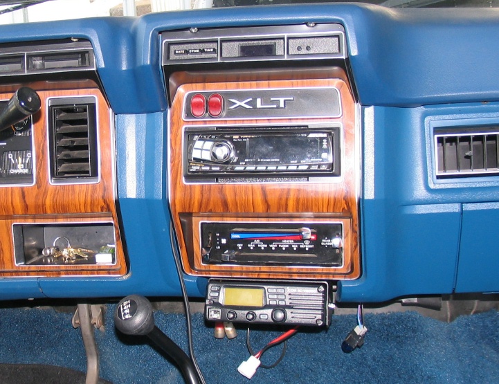 Dashboard interior of a 1984 Ford Bronco with XLT trim, wood grain accents, and aftermarket radio