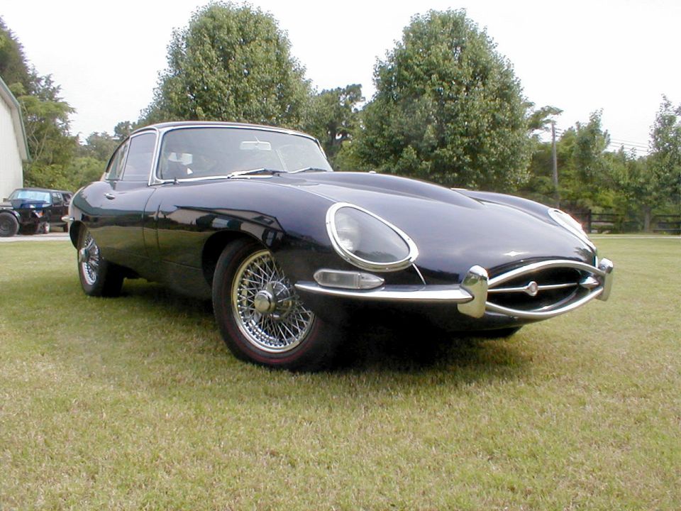 Dark blue Jaguar E-Type coupe, low right-front view, on grass