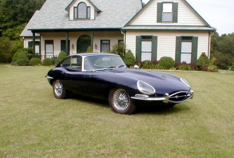 1967 Jaguar XKE - A classic 1967 Jaguar XKE coupe sits on a manicured lawn before a large house.