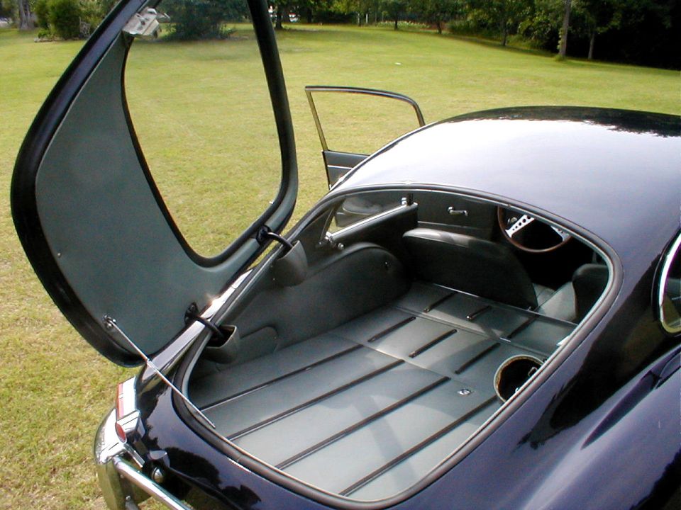Open trunk of a dark vintage car showing empty trunk floor and underside of the lid
