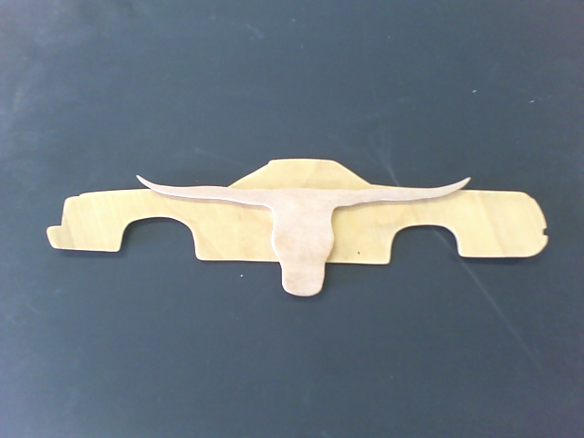 Wooden cutout of a pickup truck profile with a longhorn skull graphic superimposed