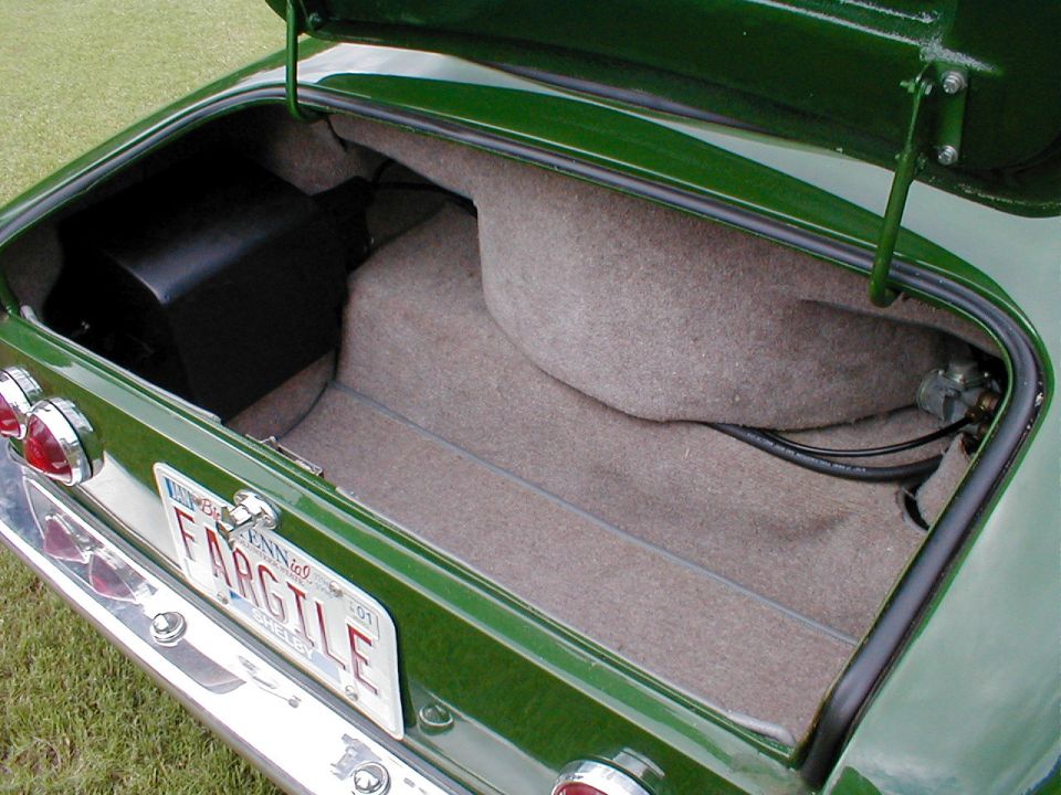 Carpeted open trunk of a dark green classic car with FARGILE Tennessee vanity plate