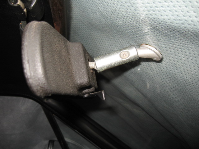 Interior door latch mechanism with a metal rod extending from a black plastic housing