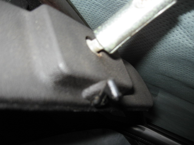 Close-up of a car's interior door handle mechanism, showing the plastic housing and metal rod